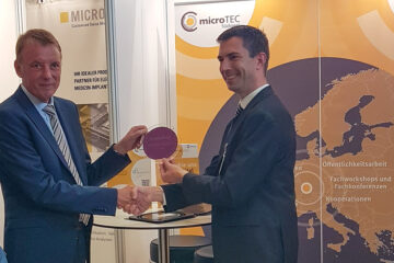 The picture shows Minister of State Jörg Krauss on the left and Prof. Dr. Niels Quack, Managing Director at IMS CHIPS, on the right at the Cluster Conference 2025 in Baden - Baden handing over a wafer from IMS CHIPS to Mr. Krauss.