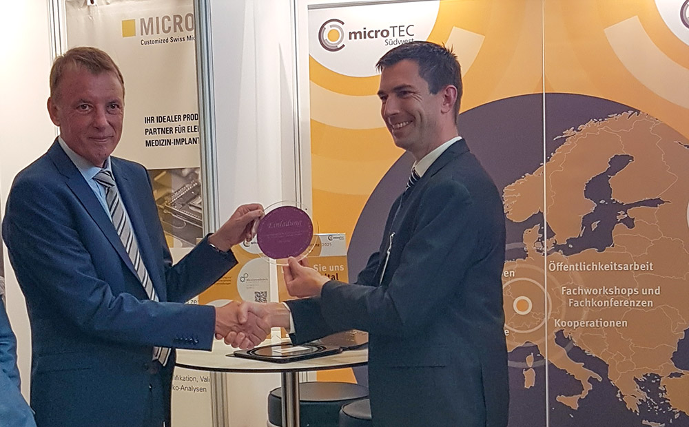The picture shows Minister of State Jörg Krauss on the left and Prof. Dr. Niels Quack, Managing Director at IMS CHIPS, on the right at the Cluster Conference 2025 in Baden - Baden handing over a wafer from IMS CHIPS to Mr. Krauss.